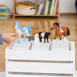Schleich Old English Sheepdog figure standing on a white wooden crate between a blue horse and a black calf, with a brown horse beside them