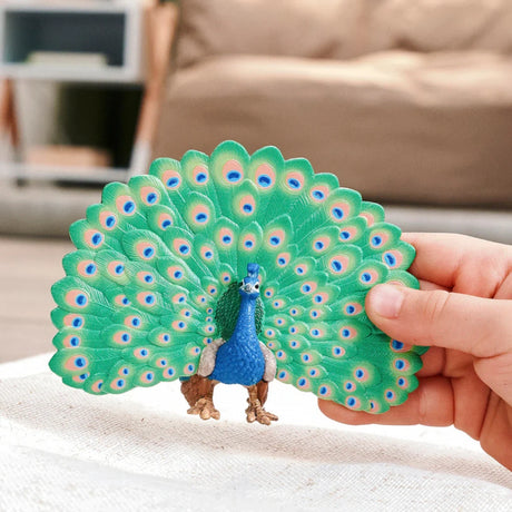 Schleich Peacock figure held in a hand with its tail feathers spread