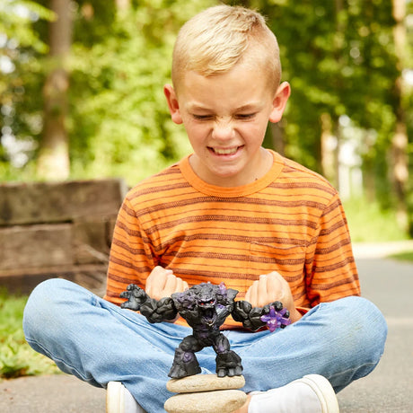 Schleich Shadow Stone Monster figure standing on two stacked stones with a seated child behind it outdoors