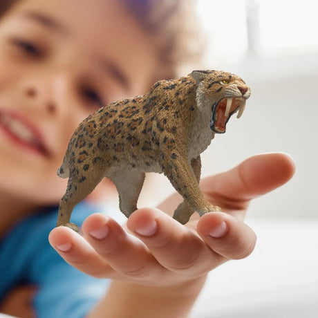 Schleich Smilodon figure held in a hand