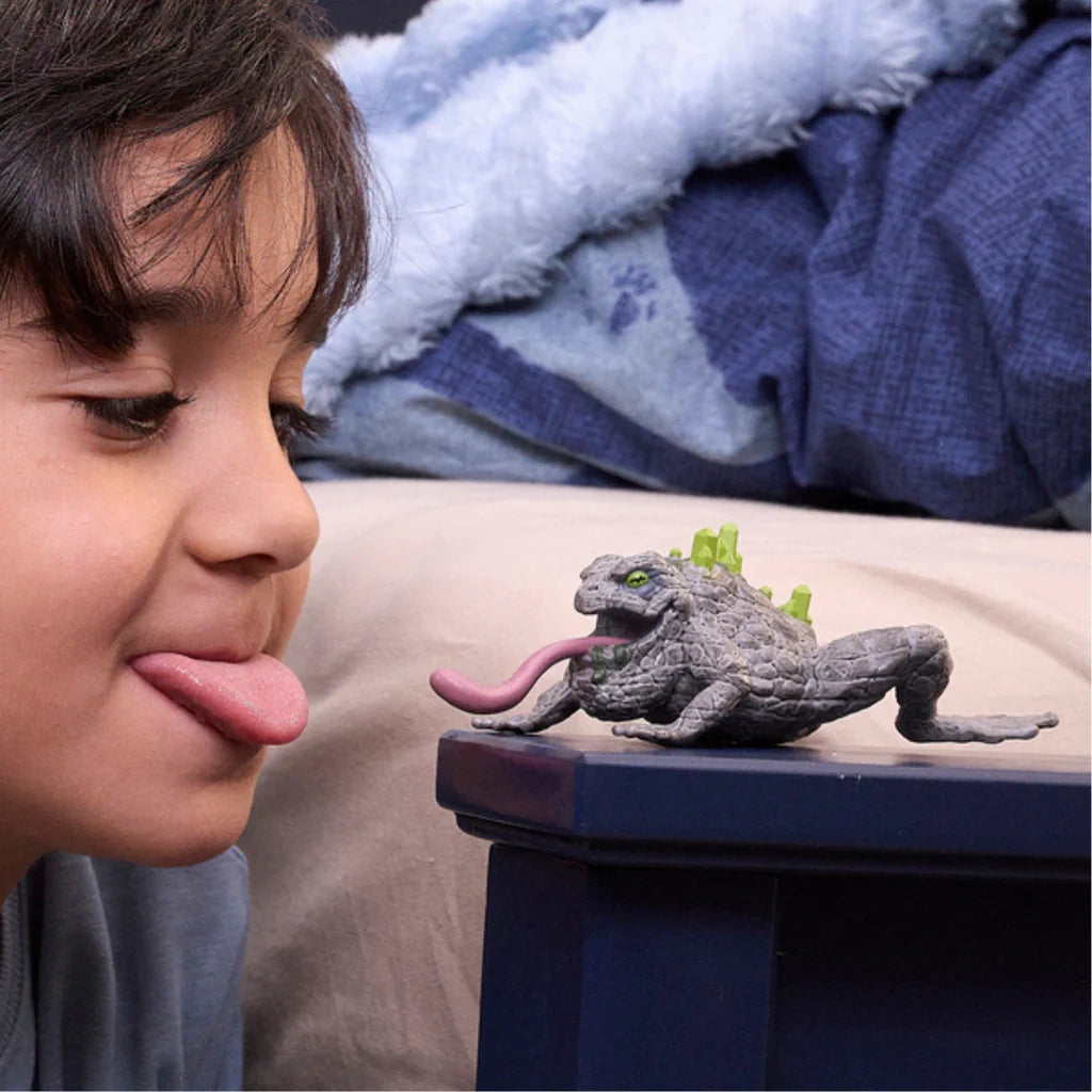 Child playing with Schleich Stone Toad 70857 with tongue extended