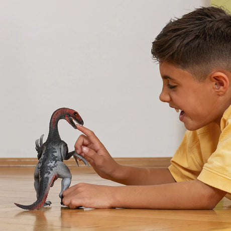 Child touching the Schleich Therizinosaurus figure on a wooden floor