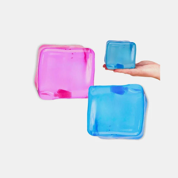 Pink and blue Scrunchems Giant Squishy Sugar Cubes with a blue cube resting on a hand for scale