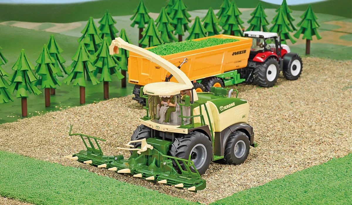 Siku Krone BiG X 580 Forage Harvester 4066 working in a field scene beside a tractor and trailer with the discharge spout positioned over the trailer