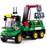 Sluban Log Trailer Large shown from the front with driver seated inside the green cab, yellow roof light, red crane, grey claw and brown log cargo secured behind the cab