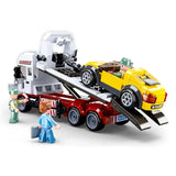 Sluban Town Car Trailer showing the yellow sports car positioned on the raised flatbed tow truck with rear loading ramps extended and three figures around the vehicle