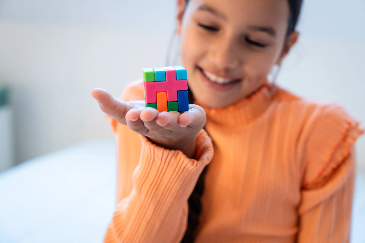 Hand holding a small colourful SmartGames IQ Quub cube