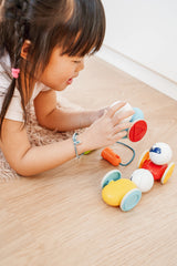 Child holding a red SmartMax My First Wobbly Cars piece beside two car pieces