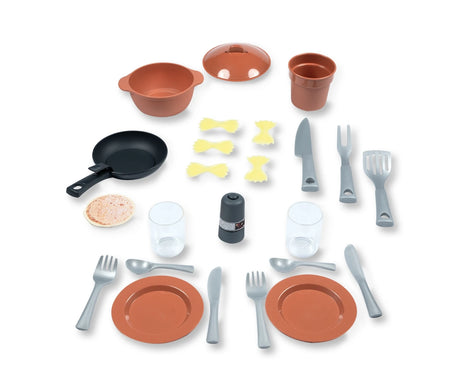 Smoby Kitchen Island accessories arranged on a white background, including orange plates, cooking pot and lid, black frying pan, toy pasta, cups, cutlery and cooking utensils.
