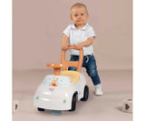 Young child standing behind the white Smoby Winnie the Pooh ride on car, holding the orange rear handle while pushing the vehicle.