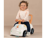 Young child sitting on the white Smoby Winnie the Pooh ride on car, holding the orange steering wheel with Winnie the Pooh illustrations visible on the front.