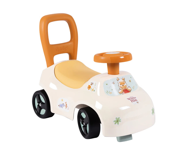 Smoby Winnie the Pooh Auto Ride On viewed from the front and side, showing its white body, orange steering wheel and rear handle, yellow seat, black wheels and Winnie the Pooh illustrations.