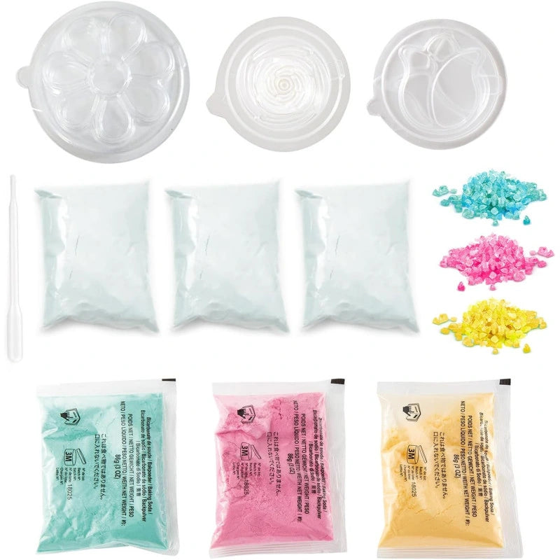 So Bomb DIY Flower Bath Bomb Kit ingredients and accessories arranged on a white background, including packets of bath bomb powders, coloured decorations and flower moulds.