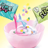 Pink mixing bowl containing white and pink slime as colourful confetti pieces, silver glitter and a blue mermaid tail decoration are added.