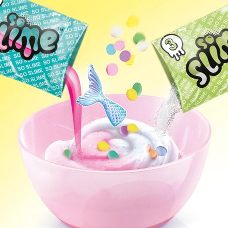 Pink mixing bowl containing white and pink slime as colourful confetti pieces, silver glitter and a blue mermaid tail decoration are added.