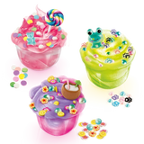 Three decorated So Slime Pop Style creations in clear pots: pink slime topped with a rainbow lollipop and sweets, green slime with a frog charm and paw prints, and purple slime with a coconut drink decoration.