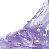 Close-up of transparent purple So Slime Pool Party slime stretched across a white background, containing small colourful beach ball decorations and white foam beads.