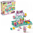 So Slime Flower Shop 2 in 1 retail packaging displayed beside the assembled turquoise flower shop stand with striped canopy, decorated pink slime pots, colourful flowers, glitter and yellow watering can.