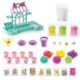 So Slime Flower Shop kit contents showing the turquoise flower shop stand, striped canopy, yellow watering can, purple flower moulds, eight pink pots, three coloured slime packets, white slime, decorative flowers, charms and glitter packets.