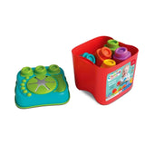 Soft Clemmy Sensory Bucket with red container holding colourful building blocks and turquoise textured lid placed separately beside it, showing green stacking studs and the central flower shaped opening.