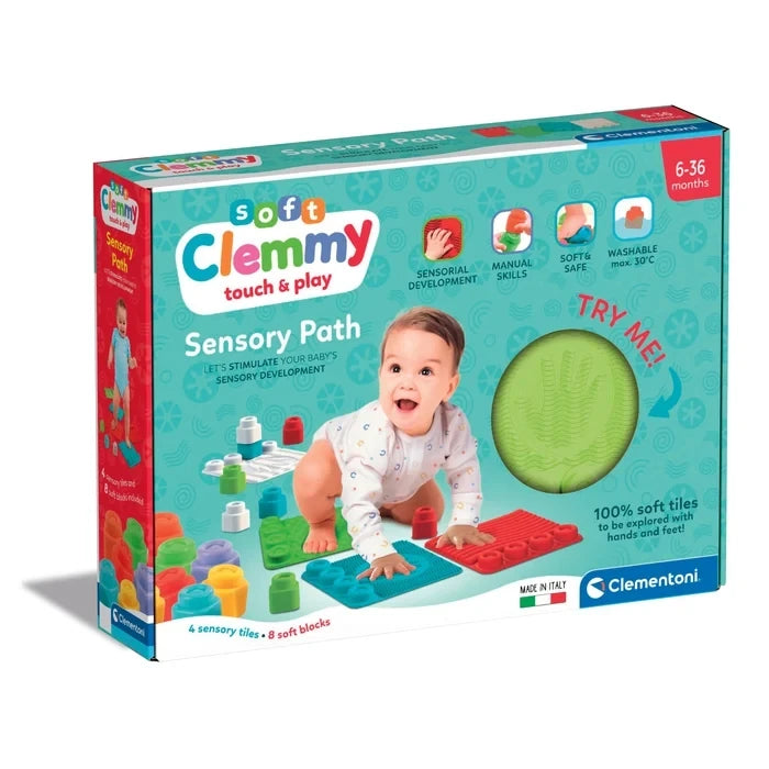 Clementoni Soft Clemmy Touch & Play Sensory Path retail box showing a crawling baby, colourful sensory tiles, eight soft blocks and a green textured tile visible through the packaging window.
