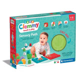 Clementoni Soft Clemmy Touch & Play Sensory Path retail box showing a crawling baby, colourful sensory tiles, eight soft blocks and a green textured tile visible through the packaging window.