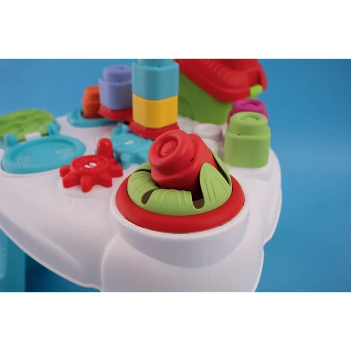 Close-up of the Soft Clemmy Sensory Table showing a red soft block positioned inside a green and red circular opening, with colourful blocks and gears behind it.