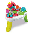 Soft Clemmy Touch & Play Sensory Table with white tabletop, yellow and green legs, red roofed house, colourful soft blocks, rotating gears and blue pop-it panel on a white background.