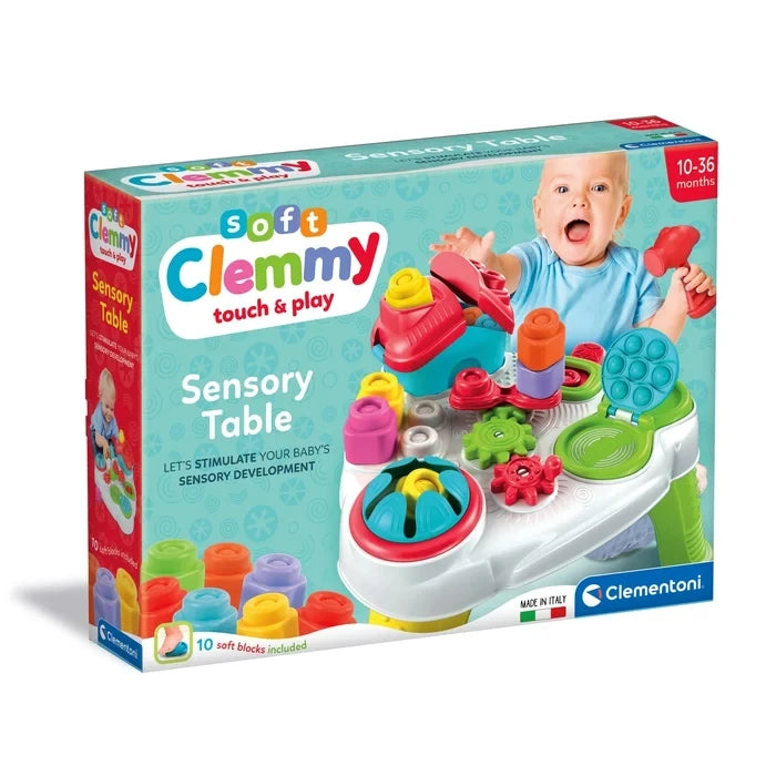 Clementoni Soft Clemmy Touch & Play Sensory Table retail packaging showing the colourful activity table, baby holding a red hammer, 10 soft blocks included and 10 to 36 months age marking.