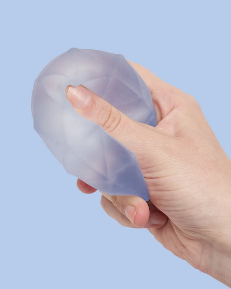 Speks Gump Surface Burst squishy being squeezed by hand, showing the raised angular textured surface