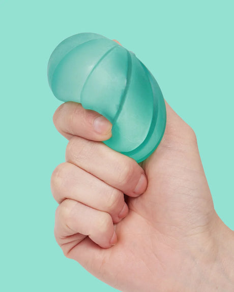 Speks Gump Surface Edge squishy being squeezed by hand, showing the raised segmented turquoise surface