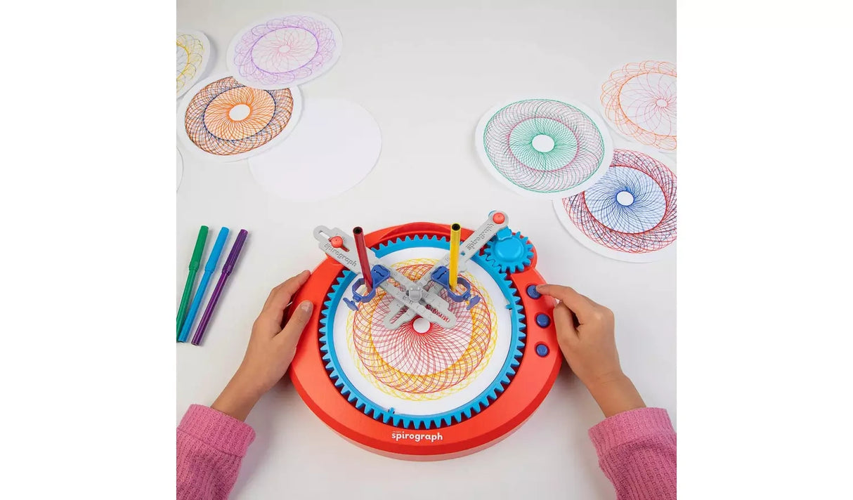 Spirograph Electronic Machine drawing a spiral pattern on a table with markers beside it