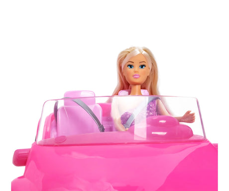 Front close-up of Steffi Love doll seated in the pink Beach Car, wearing a grey seatbelt across her purple floral dress behind the transparent windscreen.