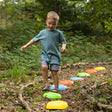 Child stepping on forest-trail styled textured stepping stones in bright colours