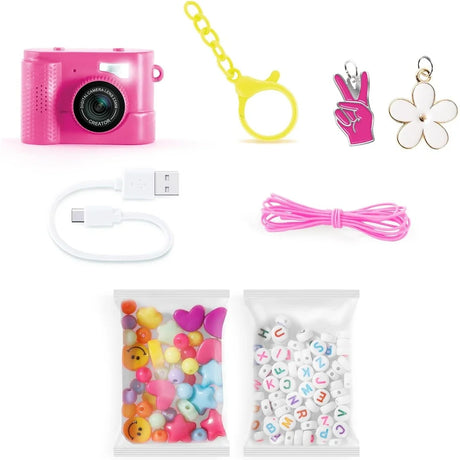 Style 4 Ever Mini Cam Bag Charm Kit contents showing a pink digital camera, yellow keychain clip, pink cord, USB-C charging cable, flower and hand charms, colourful shaped beads and white alphabet beads.