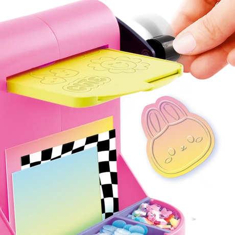 Close-up of the pink Style 4 Ever Scrapbooking Studio Pro embossing machine with a yellow embossing plate and black turning handle, alongside a pastel coloured bunny face decoration with raised details.