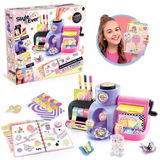 Style 4 Ever Scrapbooking Studio Pro retail box displayed beside the assembled purple and pink workstation, an open decorated journal, colourful paper sheets, decorative stickers and a girl holding a finished scrapbook.