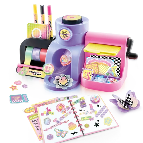 Assembled Style 4 Ever Scrapbooking Studio Pro showing colourful tape rolls, three markers, pink embossing machine, yellow plate and craft storage compartments, with an open decorated scrapbook, raised stickers and paper flower decorations in front.