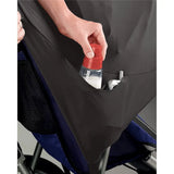 Close up of the black shade fabric pocket on a stroller, showing a hand placing a baby bottle with a red cap into the pocket opening, with blue seat fabric and stroller frame parts visible behind