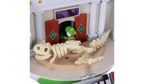 Close-up of the Yoshi Egg Playset museum scene showing a cream dinosaur skeleton lying across the floor, with Yoshi entering through red double doors beneath dinosaur artwork.