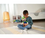 Child seated on a bedroom floor looking down at a Super Mario Luigi plush soft toy held in both hands, showing the toy held.
