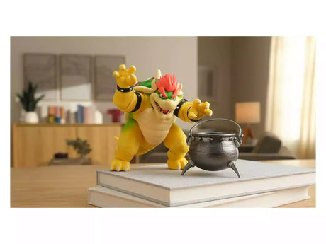 Super Mario Movie Bowser 6 inch figure displayed on a stack of books with the cauldron accessory.
