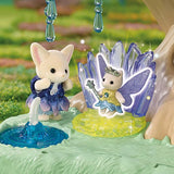 Fennec Fox baby wearing a blue and purple petal dress beside a Star Fairy with lavender wings and a wand, posed in front of tall purple crystals and a miniature blue fountain.