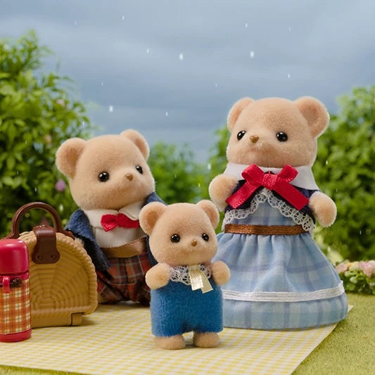Three Biscuit Bear figures shown outdoors on a picnic blanket with a basket and small accessories