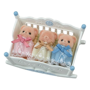 Empty white Sylvanian Families rocking cradle with blue finials, floral decorations and a yellow mattress with three raised sleeping sections.