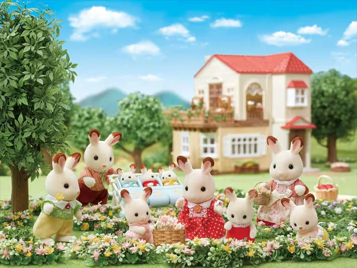 Chocolate Rabbit figures shown in a garden scene with a red roof house in the background