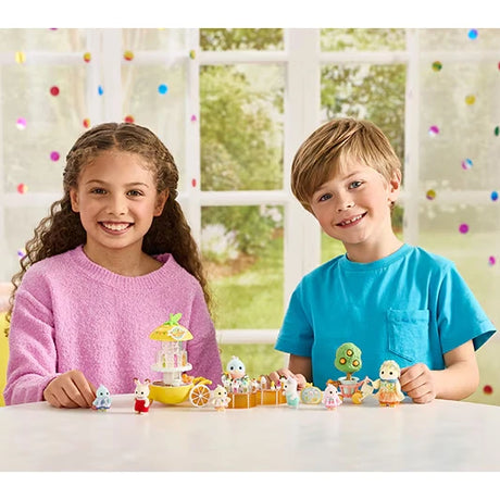 Two children sitting at a table with small Sylvanian figures and accessories