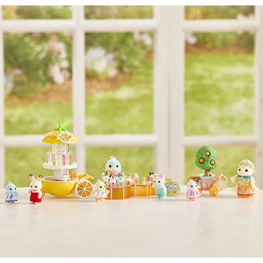 Sylvanian figures shown on a tabletop with a small ride, fruit tree and accessories