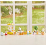 Sylvanian figures shown on a tabletop with a small ride, fruit tree and accessories