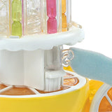 Close-up of the clear juice stand section with coloured pieces and a hand beside a side handle